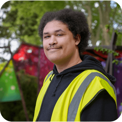Man in a reflective vest smiling, standing outdoors with colourful, abstract background